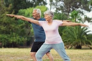 Active senior couple stretching in the park.